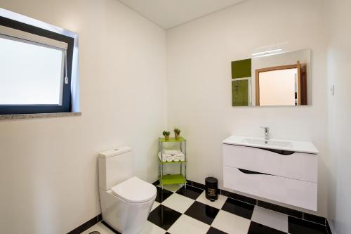 a white bathroom with a black and white checkered floor at T1 Panorâmico Ermida in Vilar da Veiga