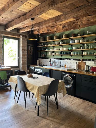 une cuisine avec une table et des chaises dans une pièce dans l'établissement Charmante maison de village, à Sénaillac-Lauzès