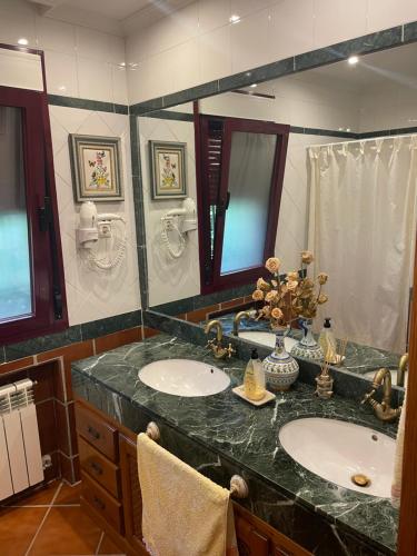a bathroom with two sinks and a large mirror at La Casita del Cerro in Candeleda