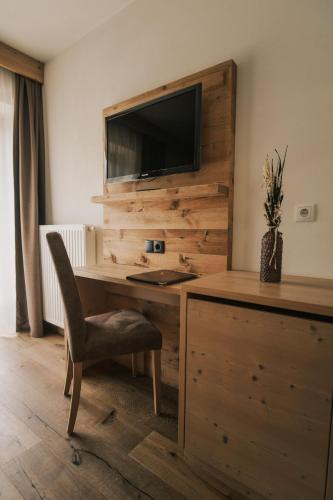 a desk with a chair and a television on a wall at Pension Moarhof in Feldthurns