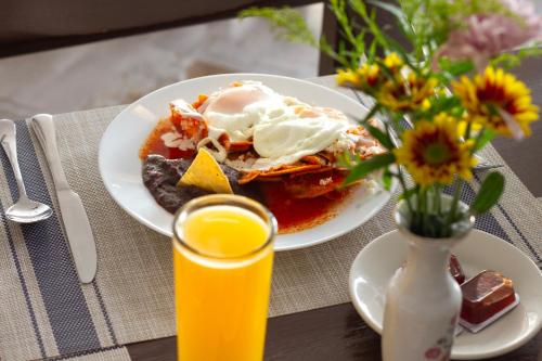 a table with a plate of food and a glass of orange juice at Hotel Bedd Express Querétaro in Querétaro