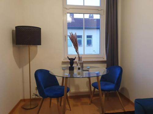 a dining room table with two blue chairs and a window at Designer Wohnung Erfurt Auenstr in Erfurt