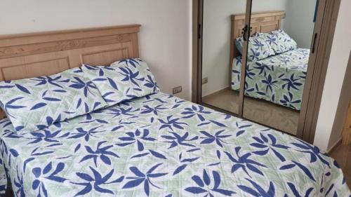 a bedroom with a bed with a blue and white comforter at Très bel Appartement avec Piscine et Jardin in Mansouria
