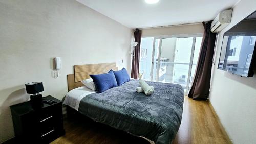 a bedroom with a bed with blue pillows and a window at GL Apts, rent Upper Pardo Miraflores - Suite 1 Hab in Lima