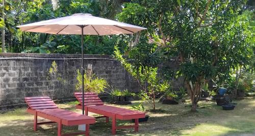two benches and an umbrella in a garden at The Esence of Sri Lanka in Ahungalla