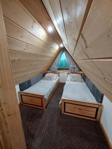 two beds in a small room with a window at Willa Maciejka in Trybsz