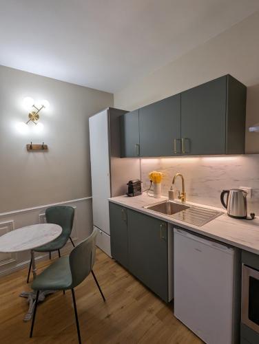 une cuisine avec des armoires vertes, une table et des chaises dans l'établissement Charmant appartement, à proximité du Château, à Versailles
