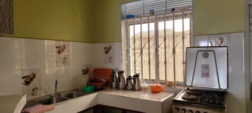 Una cocina con fregadero, estufa y ventana. en The Hoods, en Masaka