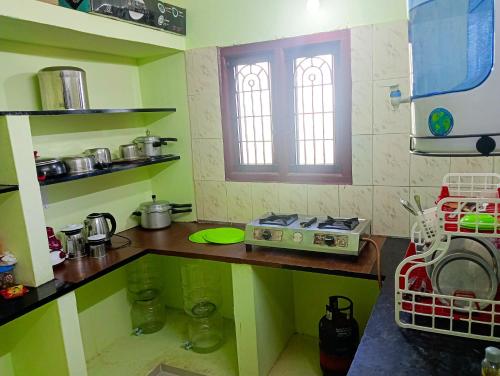 a kitchen with a counter with a microwave and a stove at JAS HOMESTAY MADURAi in Tirupparangunram