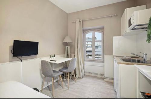 une cuisine avec une table et des chaises dans une cuisine dans l'établissement Jeu de Paume, à Versailles