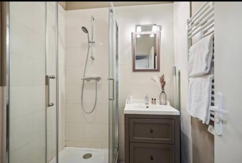 une salle de bain blanche avec une douche et un lavabo dans l'établissement Jeu de Paume, à Versailles