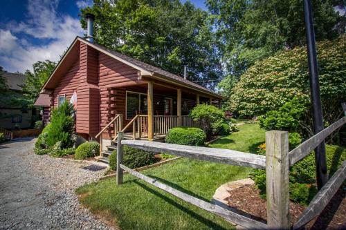 una cabaña de madera con una valla delante en Mountainaire Inn and Log Cabins, en Blowing Rock