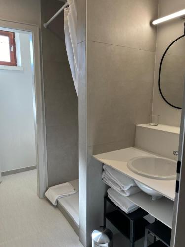 une salle de bain blanche avec un lavabo et un miroir dans l'établissement LA MAISON BERMA, à Westhoffen