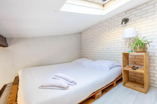 - une chambre avec un lit blanc et un mur en briques dans l'établissement GuestReady - Havre de paix près de Montmartre, à Paris