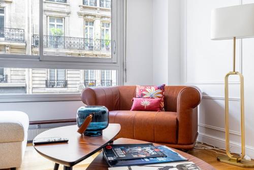 un salon avec un canapé marron et une table dans l'établissement GuestReady - Apt moderne près de l'Arc de Triomphe, à Paris