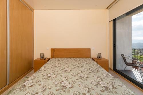a bedroom with a bed and a large window at T1 Panorâmico Ermida in Vilar da Veiga