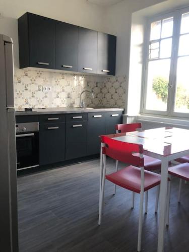 une cuisine avec une table blanche, des chaises rouges, une table et une fenêtre dans l'établissement Maison Perros Guirec Plage accessible à pieds, à La Clarté