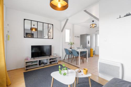 un salon avec une télévision et une table dans l'établissement La Petite Maison, aux Sorinières