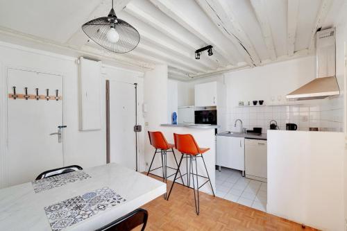 - une cuisine avec une table et deux chaises orange dans l'établissement GuestReady - Appartement arty cosy et très central, à Paris