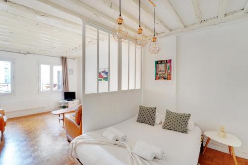 - un salon blanc avec un canapé blanc et des fenêtres dans l'établissement GuestReady - Appartement arty cosy et très central, à Paris