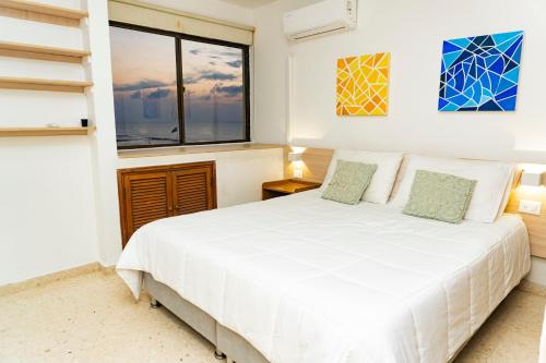 a bedroom with a white bed and a window at Apartamento frente al mar, vista al centro de Cartagena in Cartagena de Indias