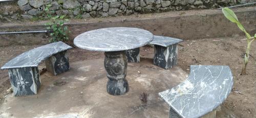 a stone table and benches sitting in a yard at Raja Hill Resorts in Kodaikānāl