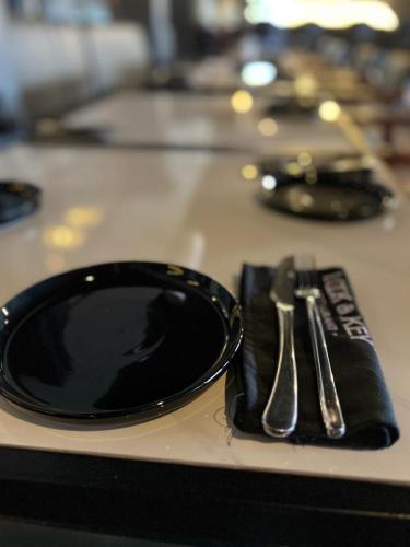 a black plate and a knife and fork on a napkin at Royal Hotel Apartments in Kampala