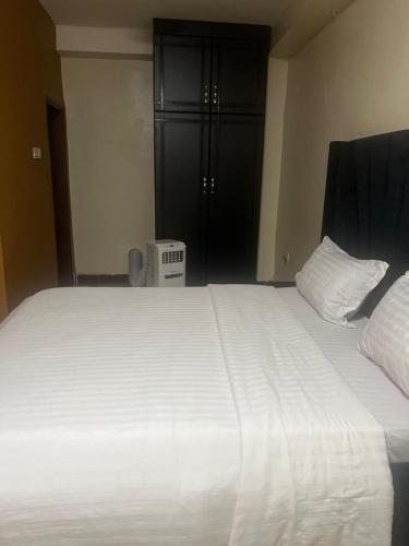 a large white bed in a room with a black closet at Royal Hotel Apartments in Kampala