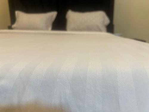 a white bed with white sheets and pillows at Royal Hotel Apartments in Kampala