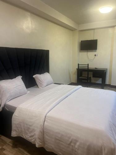 a large white bed in a room with a television at Royal Hotel Apartments in Kampala