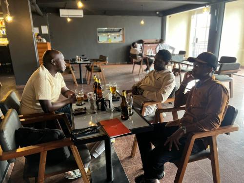 a group of men sitting at a table in a restaurant at Royal Hotel Apartments in Kampala
