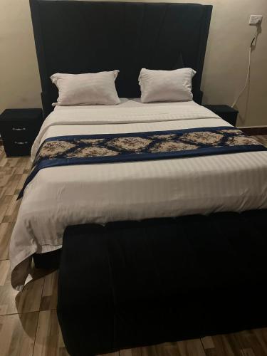 a large bed with a black headboard and white sheets at Royal Hotel Apartments in Kampala