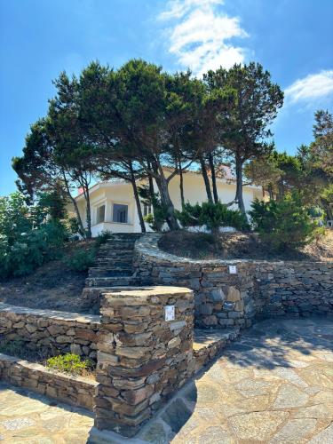 a stone wall with trees in front of a house at Villa Haass in Stintino