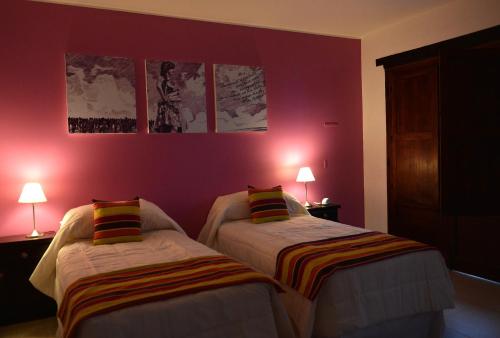 two beds in a room with pink walls at Posada de los Poetas Hotel Boutique in San Lorenzo