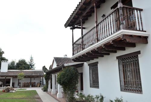 a white building with a balcony and a yard at Posada de los Poetas Hotel Boutique in San Lorenzo