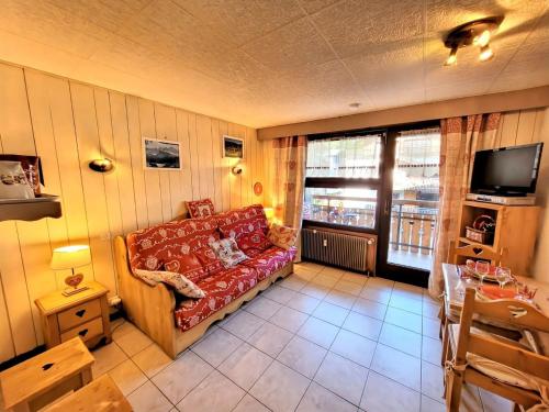 un salon avec un canapé rouge et une télévision dans l'établissement Studio au pied des pistes avec Wifi, animaux acceptés - FR-1-598-86, aux Gets