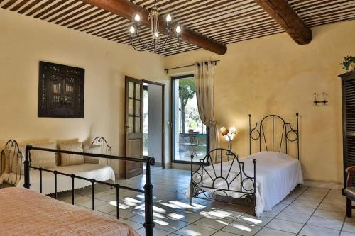a bedroom with two beds and a large window at sous la glycine de costebelle in Cheval-Blanc