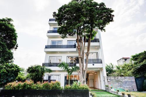 Un edificio blanco con un árbol delante. en Amaltaash by Sandane Homes, en Greater Noida