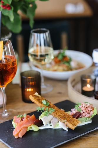 a plate of food on a table with glasses of wine at Hotel Steeds aan Zee in Katwijk
