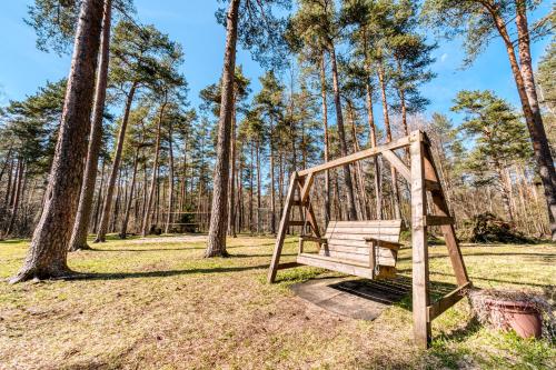a wooden swing in a park with trees at Cozy apartment in beautiful nature in Yarvekyulya