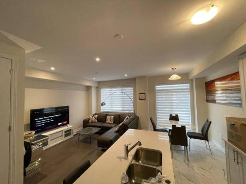 a kitchen and living room with a couch and a tv at Cozy 3-Bedrooms T-Home #Niagara in Thorold