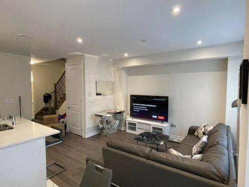 a living room with a couch and a flat screen tv at Cozy 3-Bedrooms T-Home #Niagara in Thorold