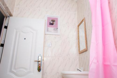 a bathroom with a pink shower curtain and a sink at UNIA Homes in Benin City