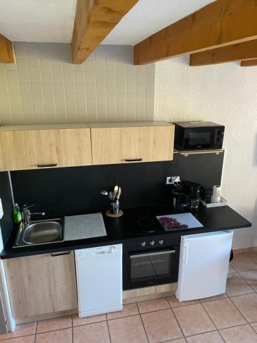 a kitchen with a black counter top and white appliances at Logement Belle vue, Reposant in Lans-en-Vercors