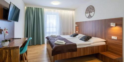 a bedroom with a bed and a desk and a television at WX Hotel in Bratislava