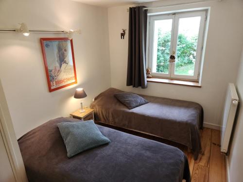 two beds in a room with a window at La Girandole Chambre d'hôtes et Location d'appartement in Arvieux