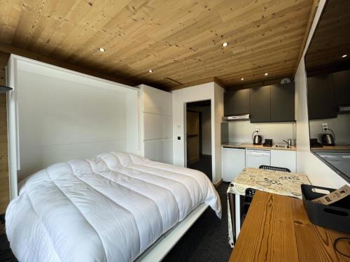 Cet appartement comprend une chambre avec un lit blanc et une cuisine. dans l'établissement Résidence Dome De Polset - VAL THORENS location: studio rénové et ensoleillé avec vue sur les montagnes MAE-9125, à Val Thorens