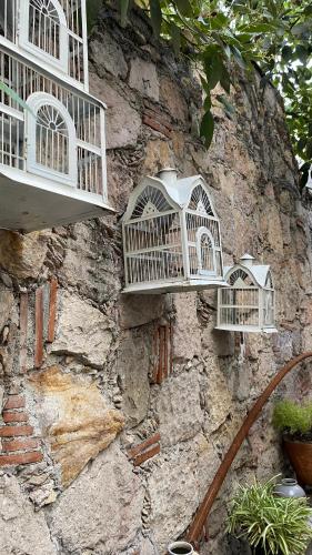 three bird cages on the side of a stone wall at Hostal San Fransiskuni in Morelia
