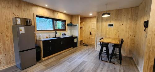 a kitchen with a refrigerator and a table in it at El Pangue Lodge in Puerto Puyuhuapi
