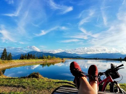 a person laying on a bench next to a lake at Dreilärchenhaus in Brixen im Thale